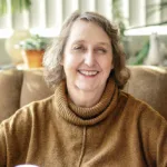 Bonnie Willey, experienced therapist at Renewed Stories Counseling, with short curly hair wearing a brown turtleneck sweater in a warm, welcoming Spokane counseling environment