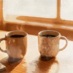 Two coffee cups side by side on wooden table with morning light, symbolizing couple considering their relationship future through discernment counseling in Spokane Two coffee cups side by side on wooden table with morning light, symbolizing couple considering their relationship future through discernment counseling in Spokane