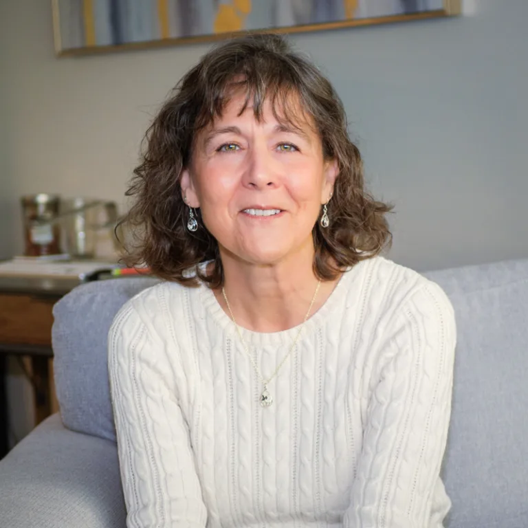 Janeen Leachman, Clinical Mental Health Counseling graduate student at Renewed Stories Counseling, smiling warmly while seated in a welcoming therapy office, providing compassionate counseling for individuals of all ages in Spokane