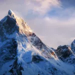 Majestic snow-covered mountain peak bathed in golden sunlight against a dramatic cloudy sky, representing the challenging but rewarding journey of rebuilding relationships Majestic snow-covered mountain peak bathed in golden sunlight against a dramatic cloudy sky, representing the challenging but rewarding journey of rebuilding relationships
